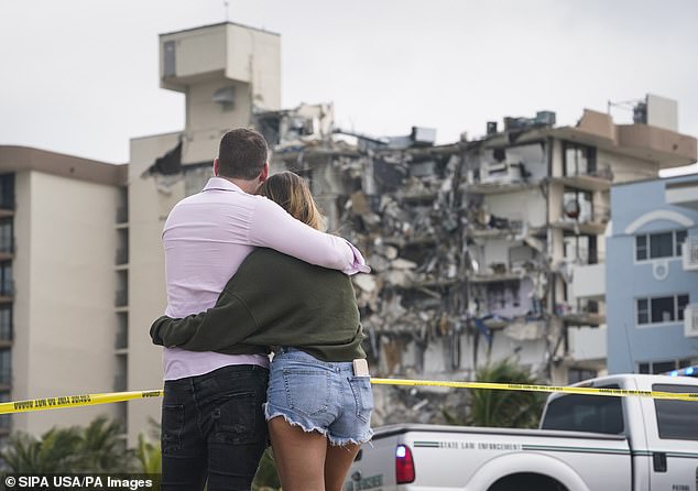 People are seen hugging outside of the partially collapsed Champlain Towers South condo in Surfside, Florida on Friday
