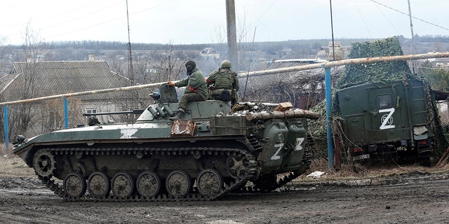 Service members of pro-Russian troops in uniforms without insignia drive an armored vehicle with the symbol "Z" painted on its side in the separatist-controlled village of Bugas during Ukraine-Russia conflict in the Donetsk region, Ukraine March 6, 2022.